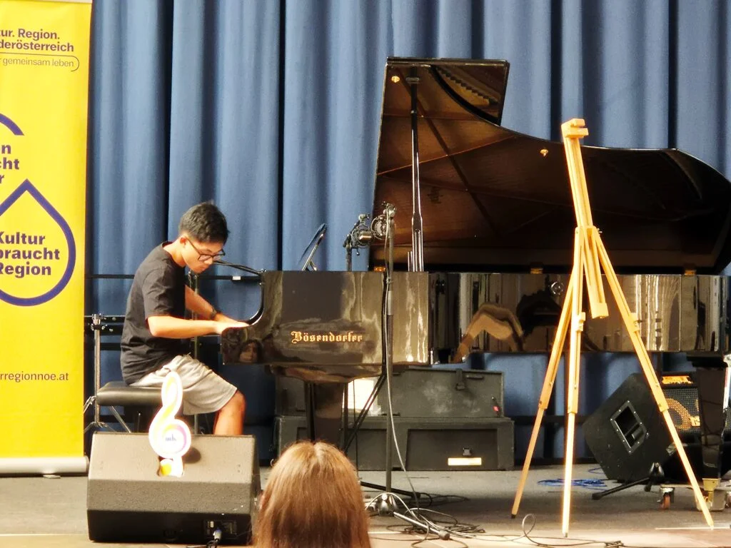 Ryan John Bacay präsentiert seine Komposition „The Walk on the Fire“ am Klavier