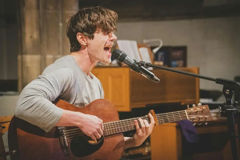 Mann singt mit einer Gitarre